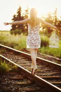 Young woman in dress balancing on a railway track Young woman in dress balancing on a railway track